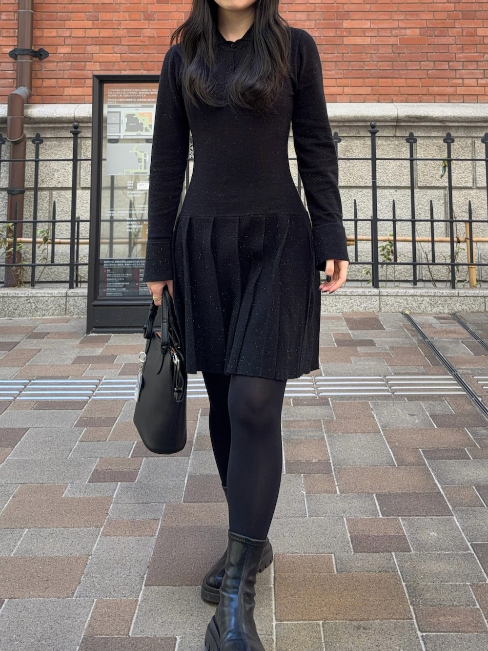 ブラック系のワンピース、ブラック系のブーツ、ブラック系のハンドバッグを着用したレディースの秋コーディネートの3枚目の写真
