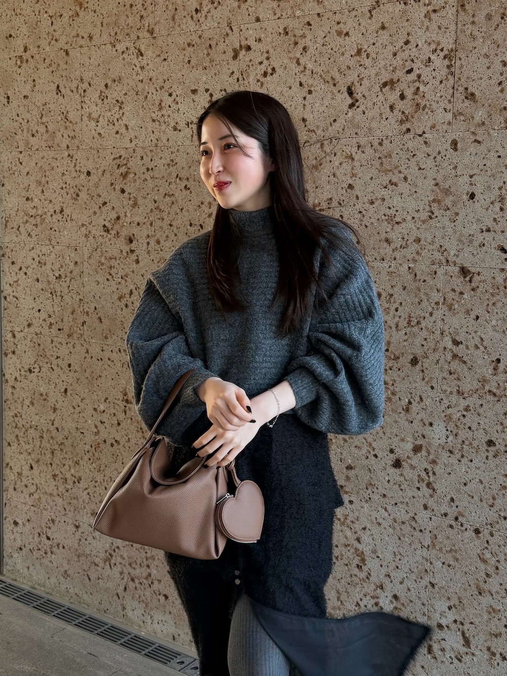 グレー系のワンピース、ブラウン系のスカート、イエロー系のハンドバッグを着用したレディースの冬コーディネートの3枚目の写真