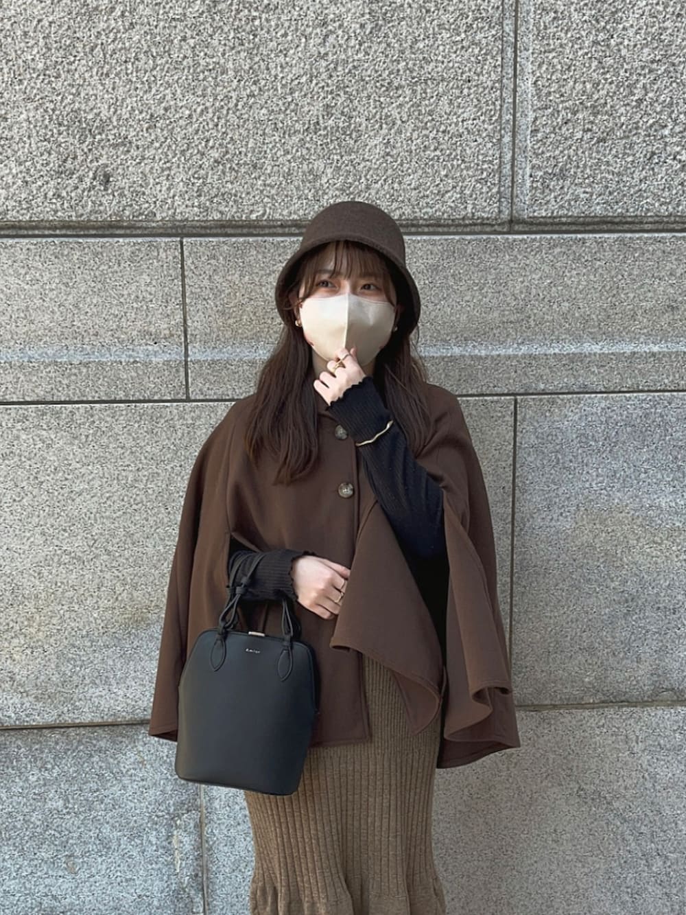 ブラウン系のポンチョ、ブラウン系のスカート、ブラック系のブーツを着用したレディースの冬コーディネートの3枚目の写真