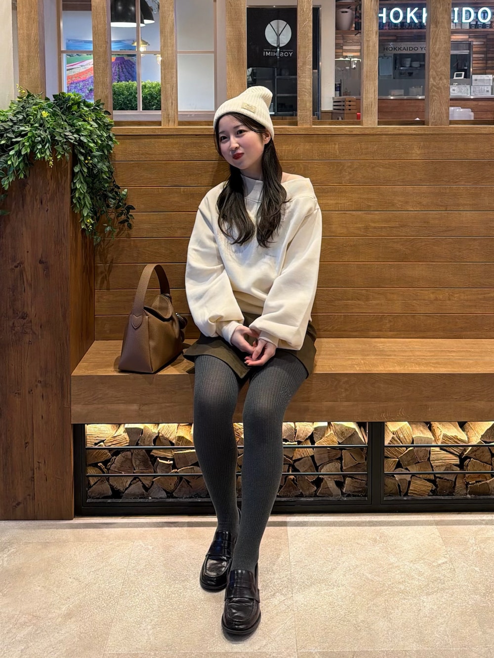 ホワイト系のスウェット、ブラウン系のスカート、イエロー系のハンドバッグを着用したレディースの冬コーディネートの2枚目の写真