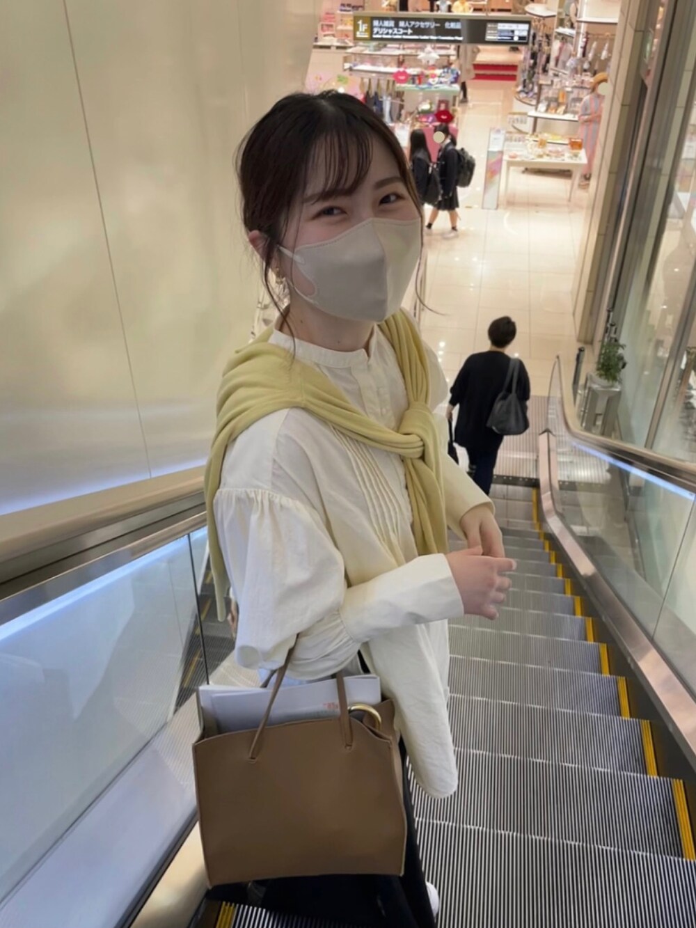 ホワイト系のシャツ/ブラウス、イエロー系のカーディガン/ボレロ、ブラック系のスカートを着用したレディースの春コーディネートの2枚目の写真