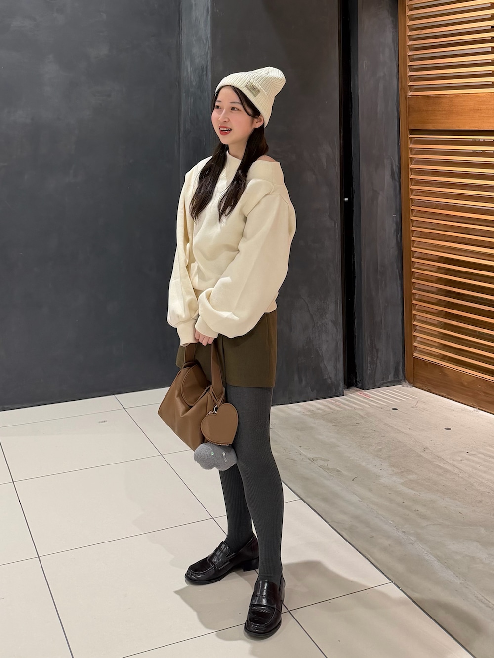 ホワイト系のスウェット、ブラウン系のスカート、イエロー系のハンドバッグを着用したレディースの冬コーディネートの3枚目の写真