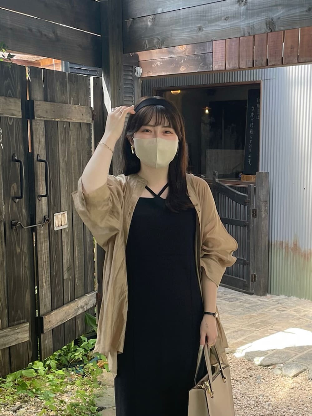 ブラック系のジャンパースカート、ベージュ系のシャツ/ブラウス、ブラック系のサンダルを着用したレディースの夏コーディネートの3枚目の写真