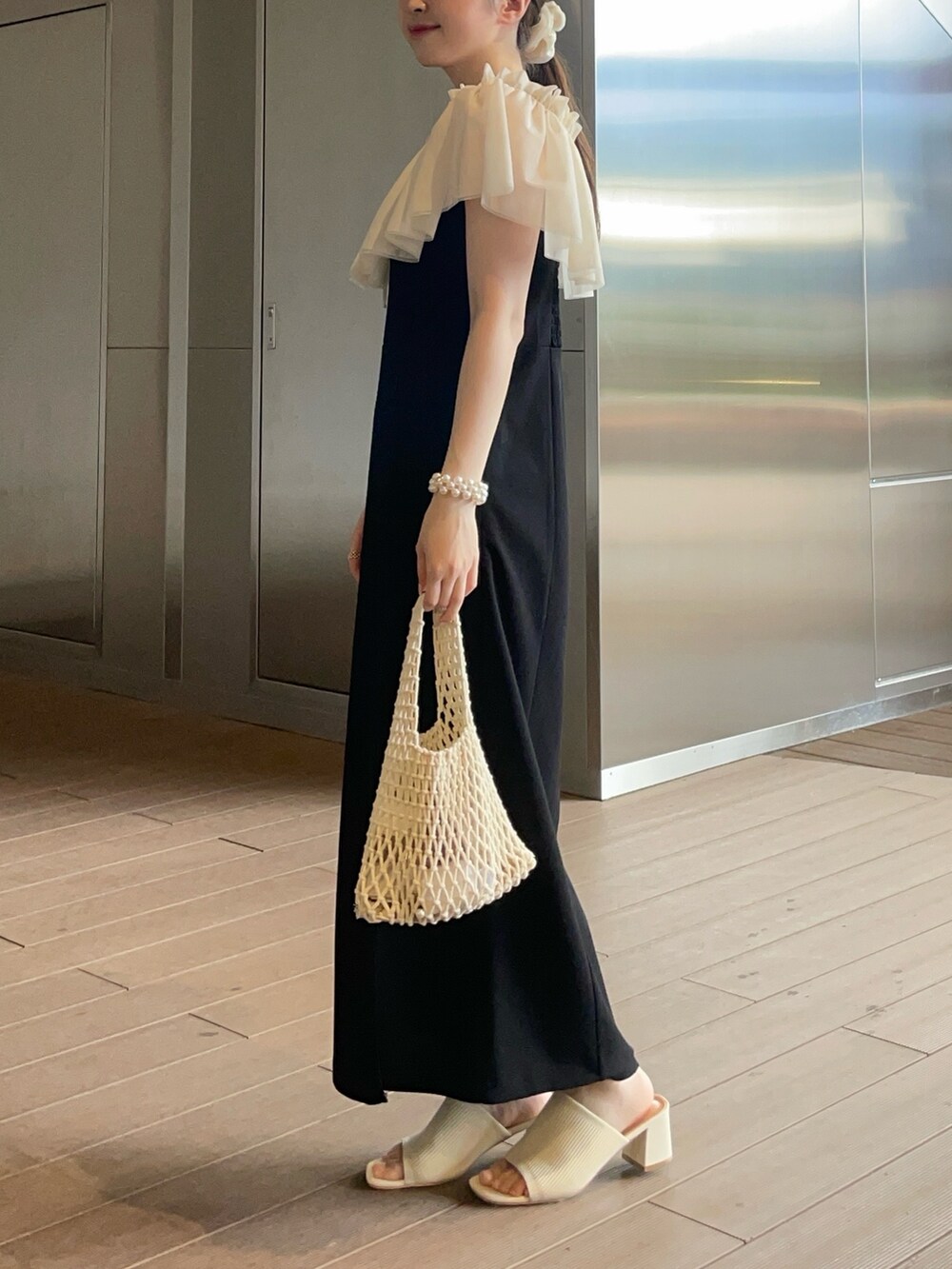 ブラック系のジャンパースカート、ホワイト系のサンダル、ホワイト系の付け襟を着用したレディースの夏コーディネートの2枚目の写真