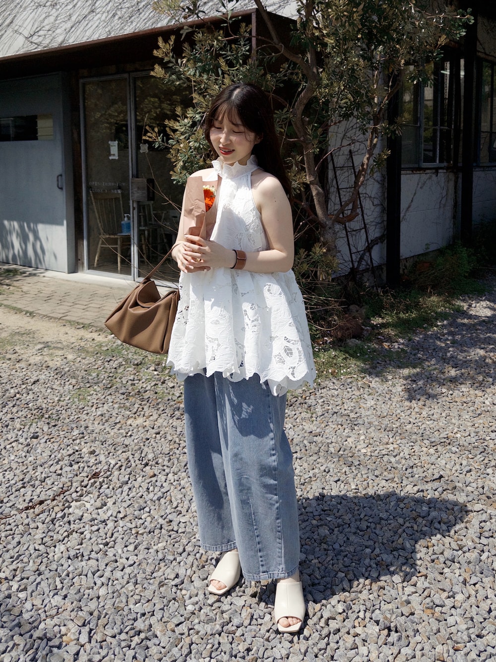 ブルー系のデニムパンツ、ホワイト系のサンダル、イエロー系のハンドバッグを着用したレディースの春コーディネートの5枚目の写真