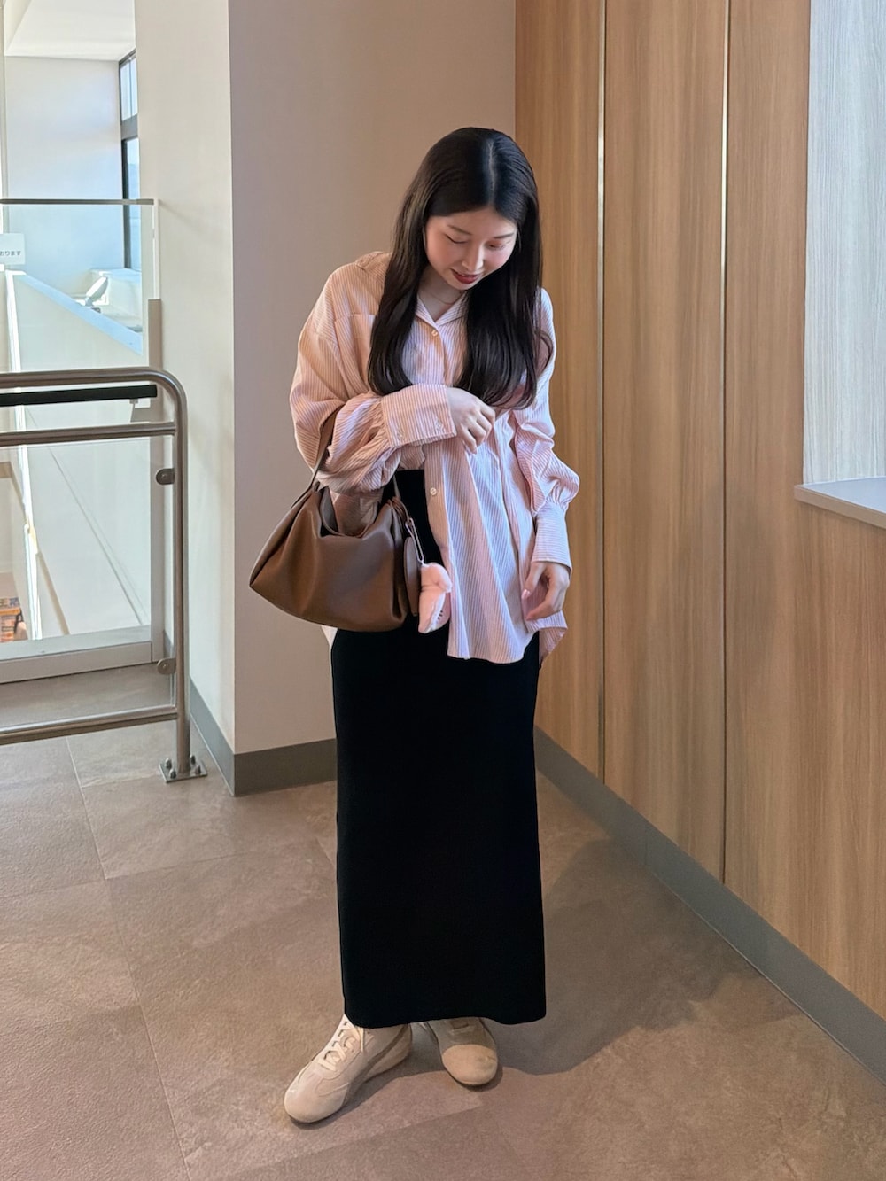 ホワイト系のスニーカー、ブラック系のスカート、イエロー系のハンドバッグを着用したレディースの春コーディネートの5枚目の写真