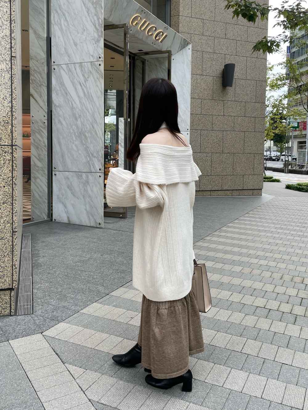 ホワイト系のニット/セーター、ブラウン系のスカート、ブラック系のブーツを着用したレディースの秋コーディネートの2枚目の写真