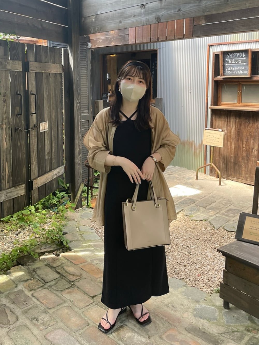 ブラック系のジャンパースカート、ベージュ系のシャツ/ブラウス、ブラック系のサンダルを着用したレディースの夏コーディネートの4枚目の写真