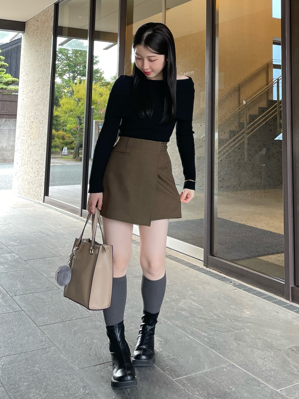 ブラック系のブーツ、ブラウン系のスカート、ブラック系のニット/セーターを着用したレディースの秋コーディネートの2枚目の写真