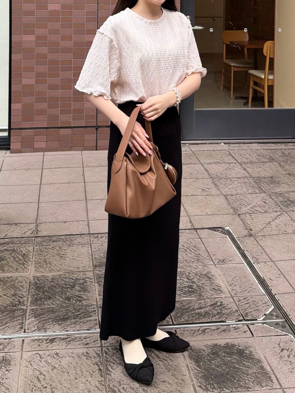 ブラック系のスカート、ホワイト系のTシャツ/カットソー、イエロー系のハンドバッグを着用したレディースの春コーディネートの3枚目の写真