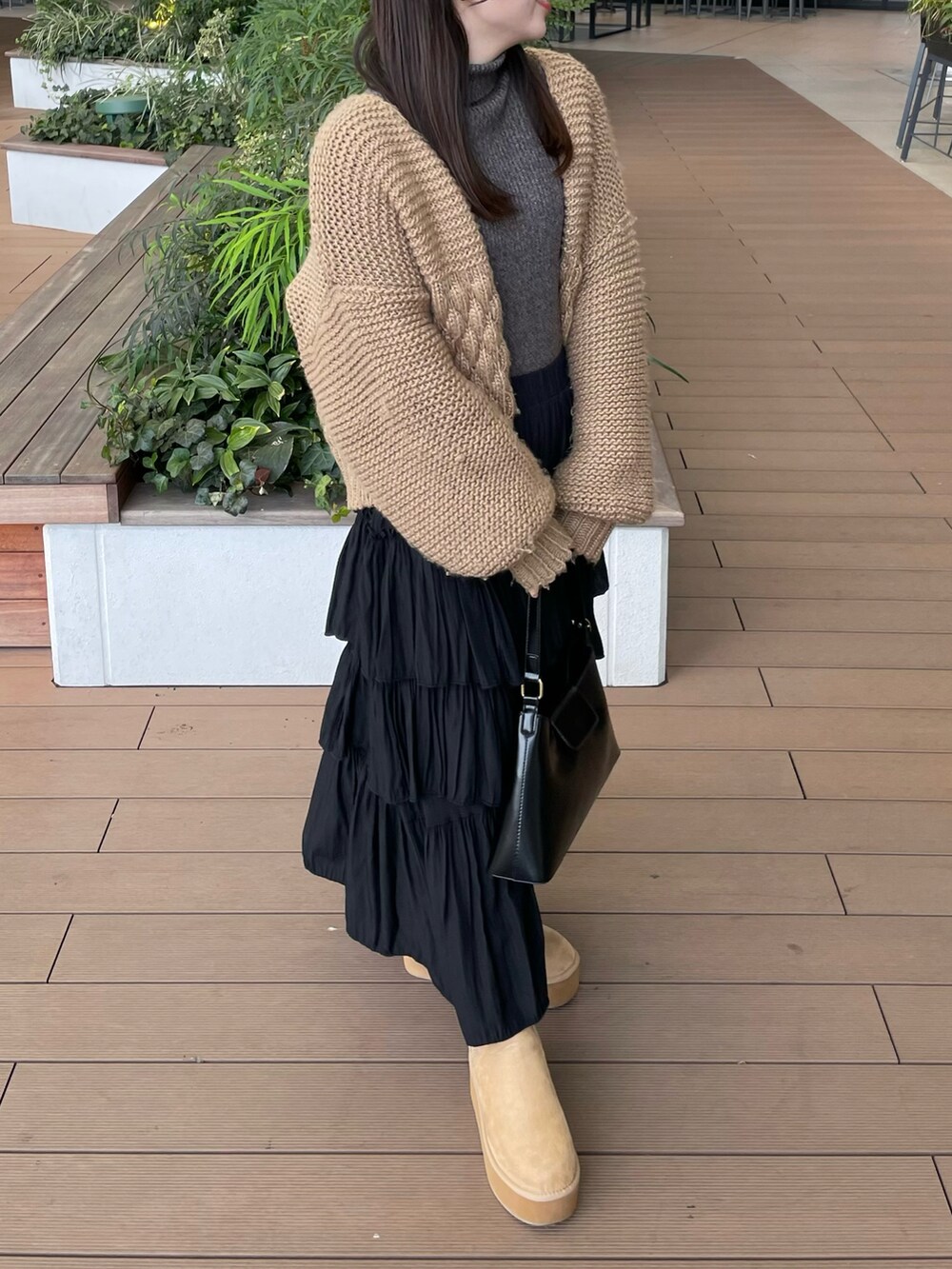 グレー系のニット/セーター、ベージュ系のカーディガン/ボレロ、ブラック系のスカートを着用したレディースの冬コーディネートの3枚目の写真