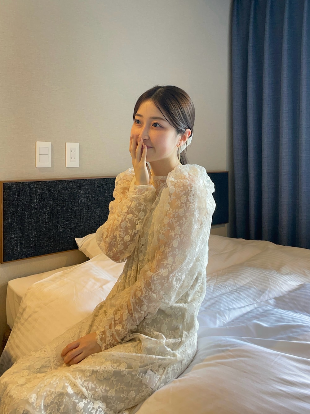 ホワイト系のワンピース、ベージュ系のバッグ、ゴールド系のパンプスを着用したレディースの春コーディネートの2枚目の写真