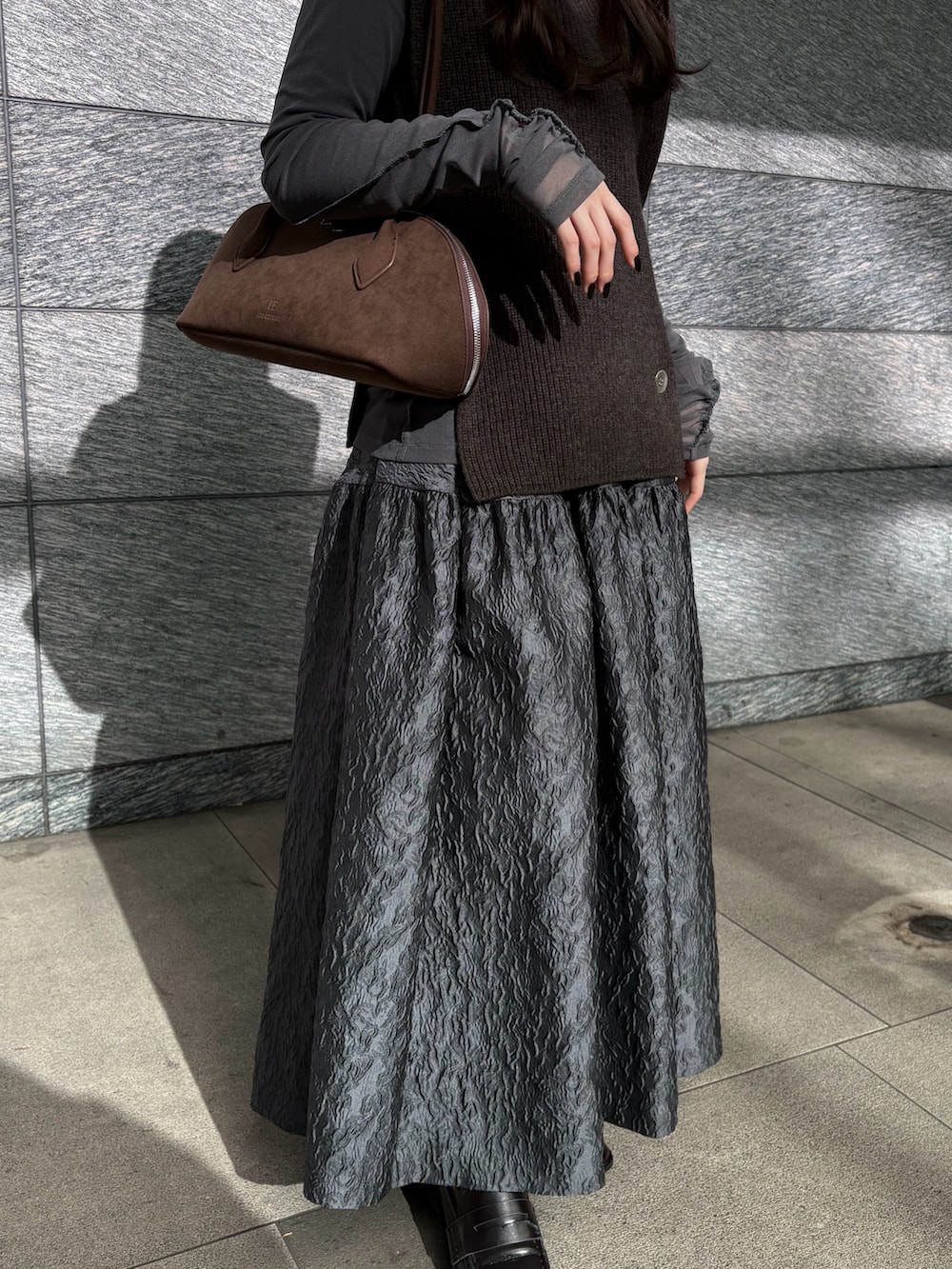 ブラウン系のニット/セーター、ブラウン系のビジネスバッグ、グレー系のTシャツ/カットソーを着用したレディースの冬コーディネートの4枚目の写真