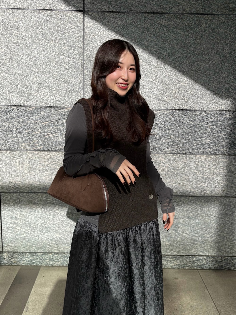 ブラウン系のニット/セーター、ブラウン系のビジネスバッグ、グレー系のTシャツ/カットソーを着用したレディースの冬コーディネートの3枚目の写真