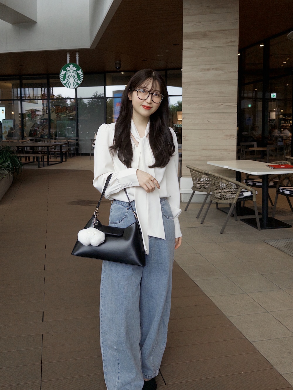 ホワイト系のシャツ/ブラウス、ブルー系のデニムパンツ、ブラック系のハンドバッグを着用したレディースの夏コーディネートの3枚目の写真