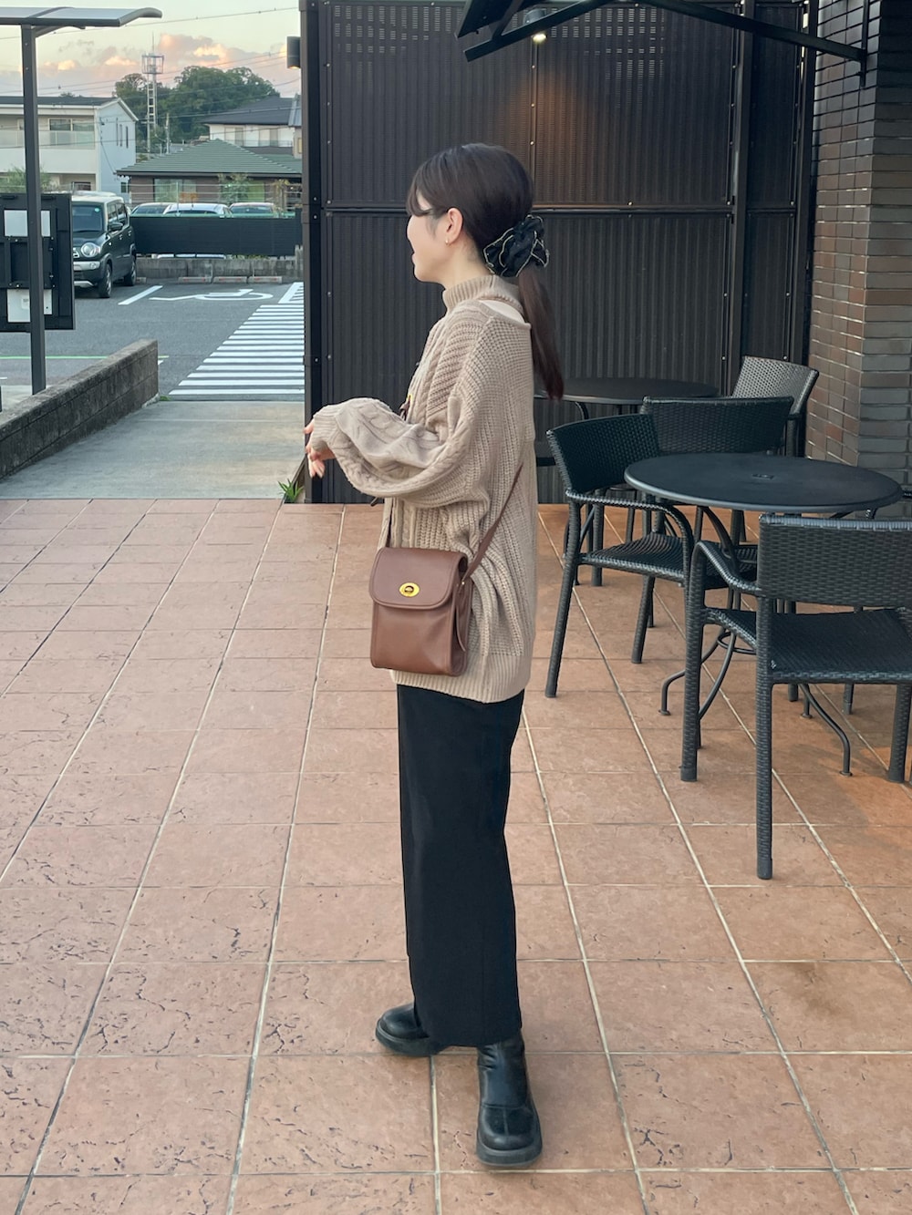 ブラウン系のニット/セーター、ブラック系のジャンパースカート、ブラック系のブーツを着用したレディースの秋コーディネートの3枚目の写真