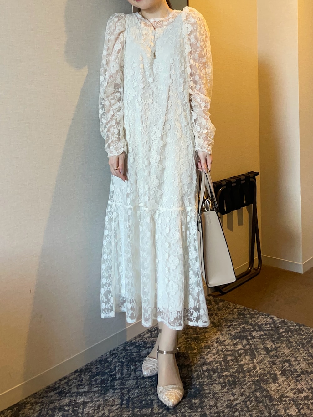 ホワイト系のワンピース、ベージュ系のバッグ、ゴールド系のパンプスを着用したレディースの春コーディネートの3枚目の写真