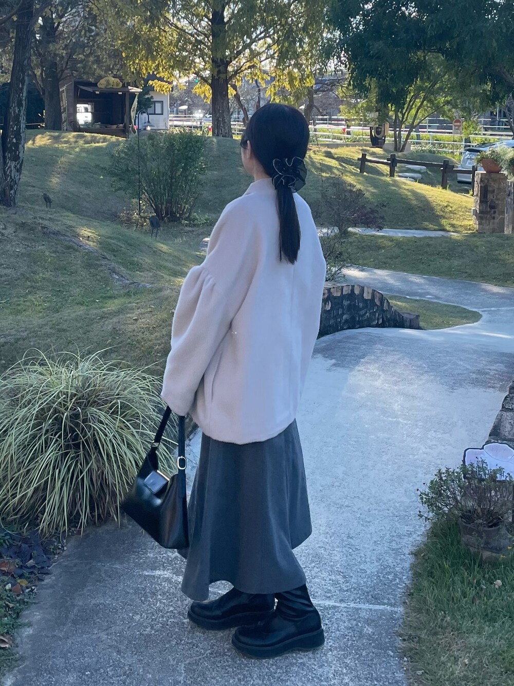 ホワイト系のニット/セーター、グレー系のワンピース、ブラック系のブーツを着用したレディースの秋コーディネートの3枚目の写真