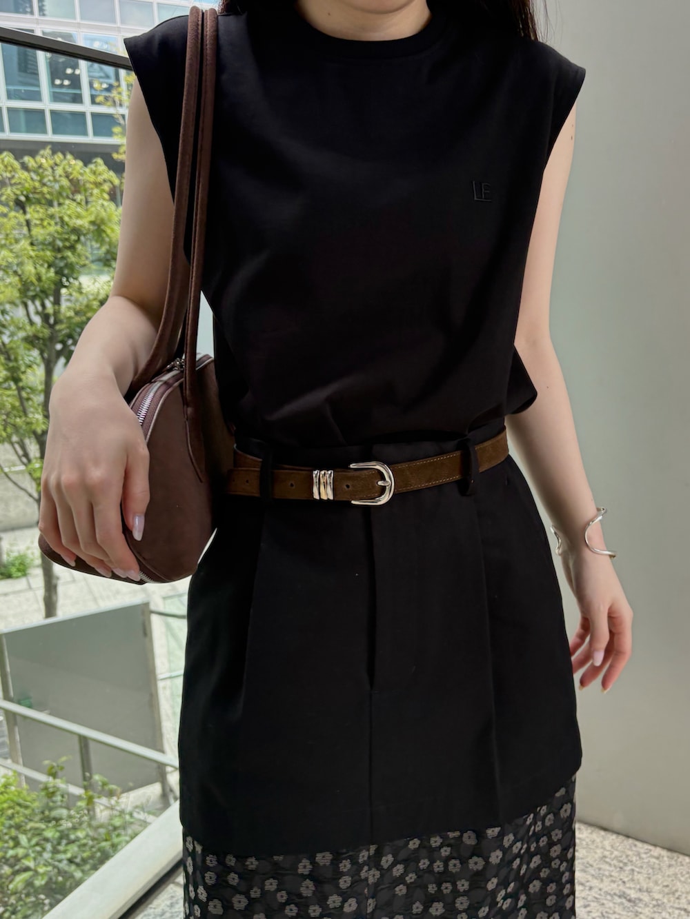 ブラウン系のビジネスバッグ、ブラック系のTシャツ/カットソー、ブラック系のスカートを着用したレディースの春コーディネートの5枚目の写真