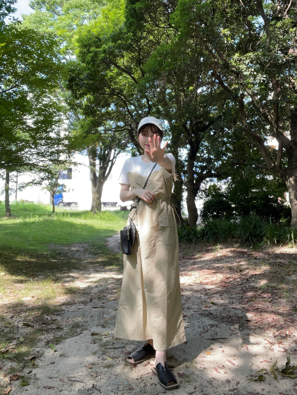 ベージュ系のワンピース、ブラック系のサンダル、ブラック系のハンドバッグを着用したレディースの夏コーディネートの2枚目の写真