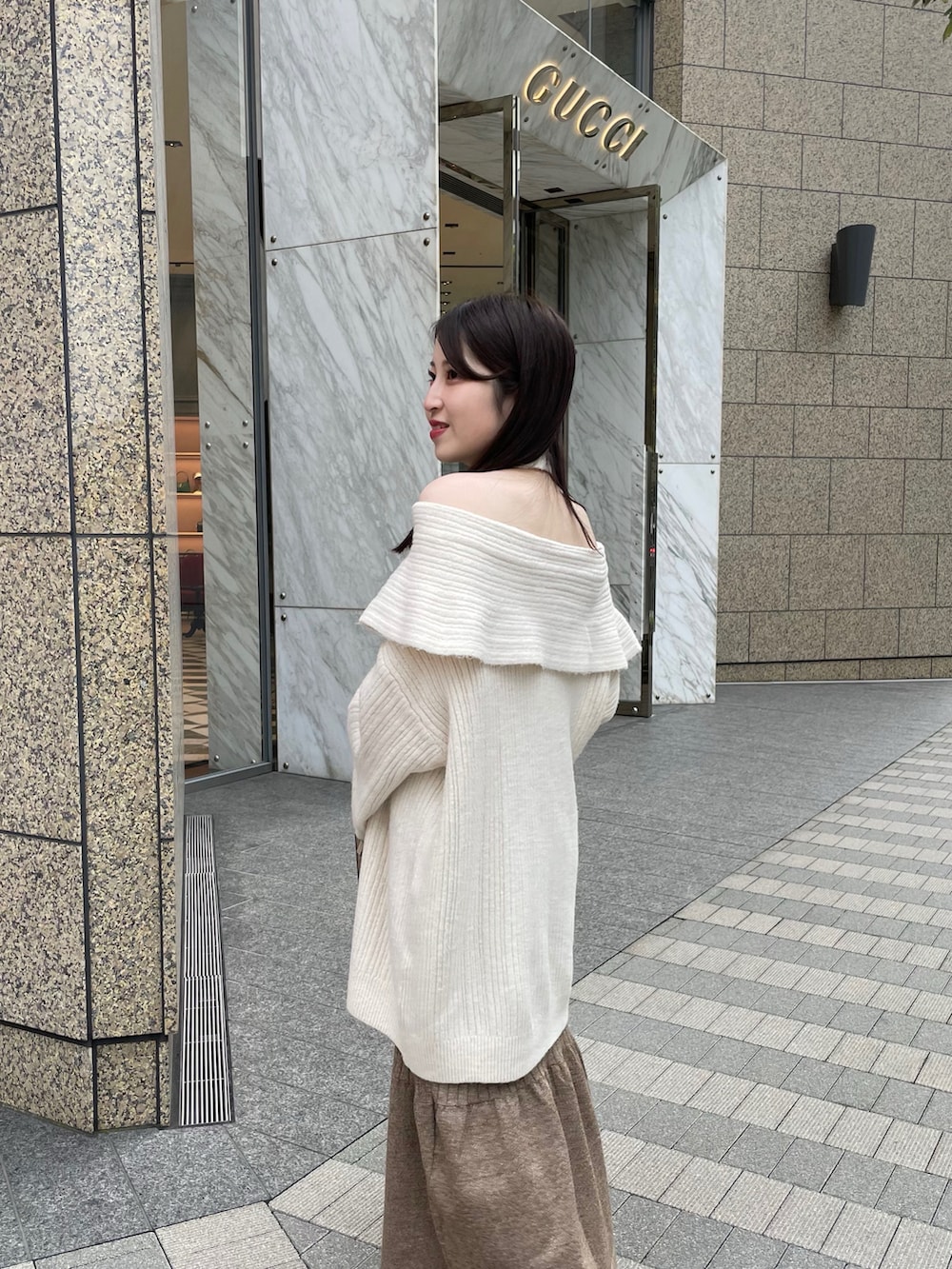 ホワイト系のニット/セーター、ブラウン系のスカート、ブラック系のブーツを着用したレディースの秋コーディネートの3枚目の写真