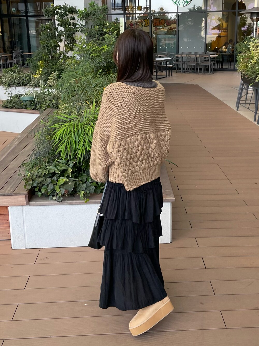 グレー系のニット/セーター、ベージュ系のカーディガン/ボレロ、ブラック系のスカートを着用したレディースの冬コーディネートの4枚目の写真