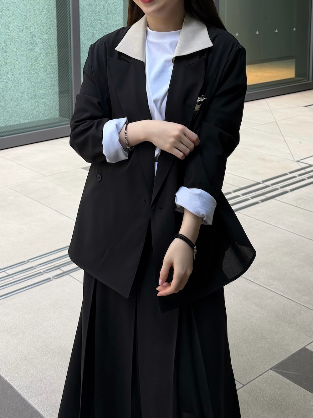 ホワイト系のTシャツ/カットソー、ブラック系のテーラードジャケット、ブラック系のスカートを着用したレディースの春コーディネートの4枚目の写真