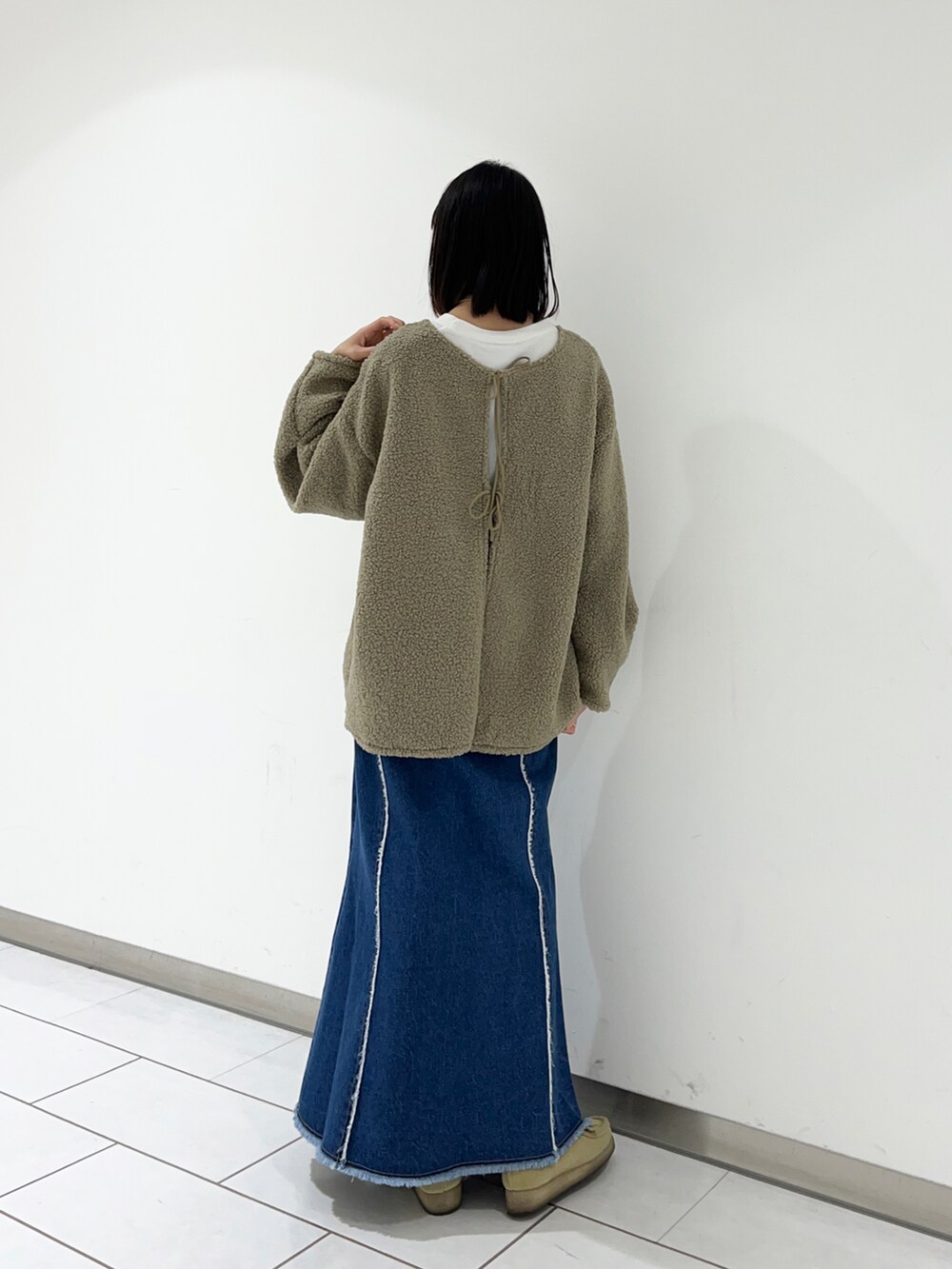 ベージュ系のモカシン/デッキシューズ、ブルー系のデニムスカート、グリーン系のTシャツ/カットソーを着用したレディースの冬コーディネートの2枚目の写真