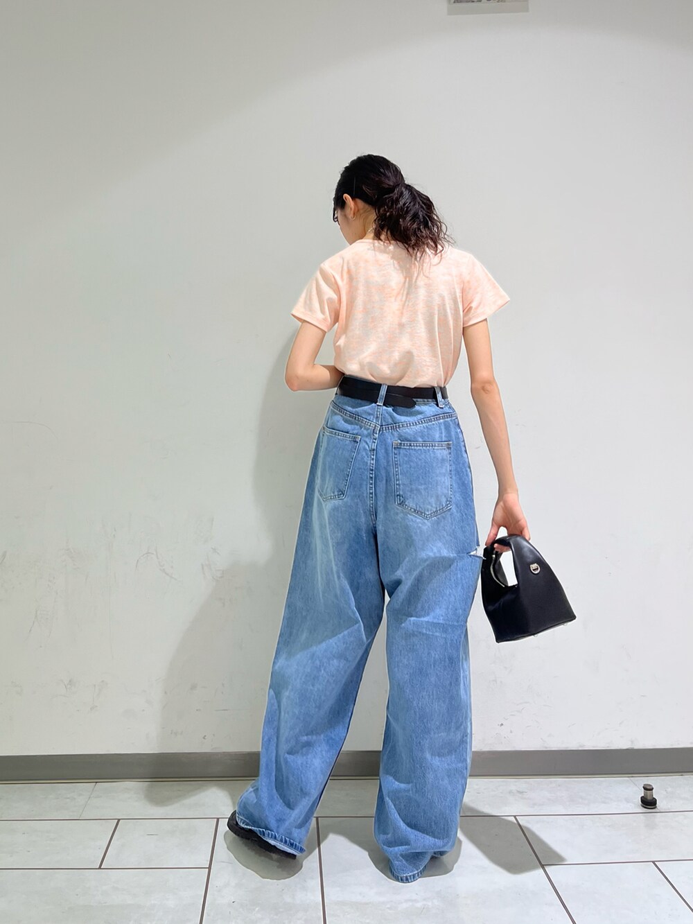 オレンジ系のTシャツ/カットソー、ブルー系のデニムパンツ、ブラック系のサンダルを着用したレディースの春コーディネートの2枚目の写真