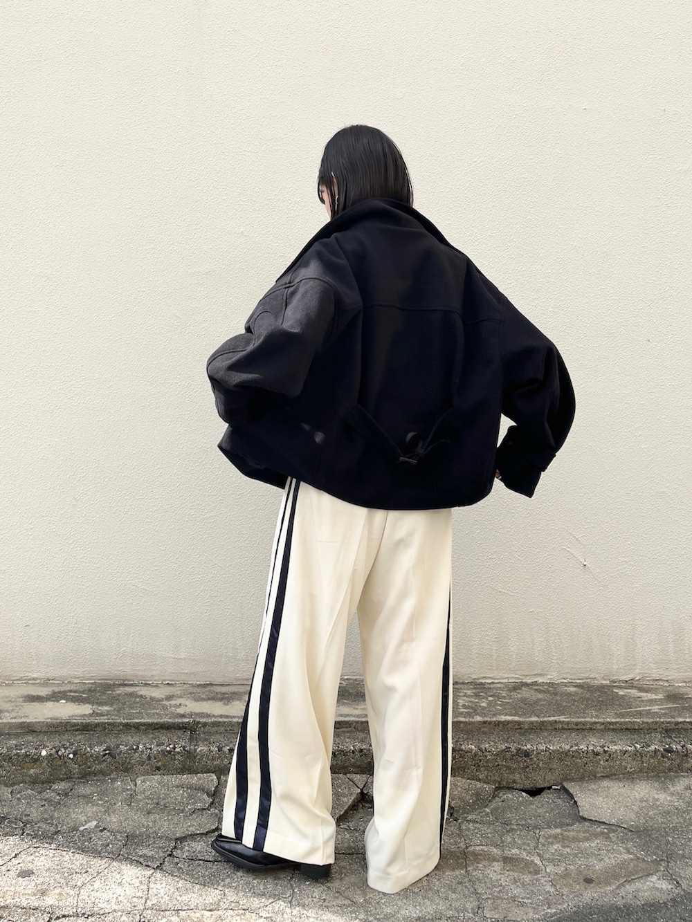 ブラック系のその他アウター、ブラック系のTシャツ/カットソー、ホワイト系のスラックスを着用したレディースの秋コーディネートの2枚目の写真