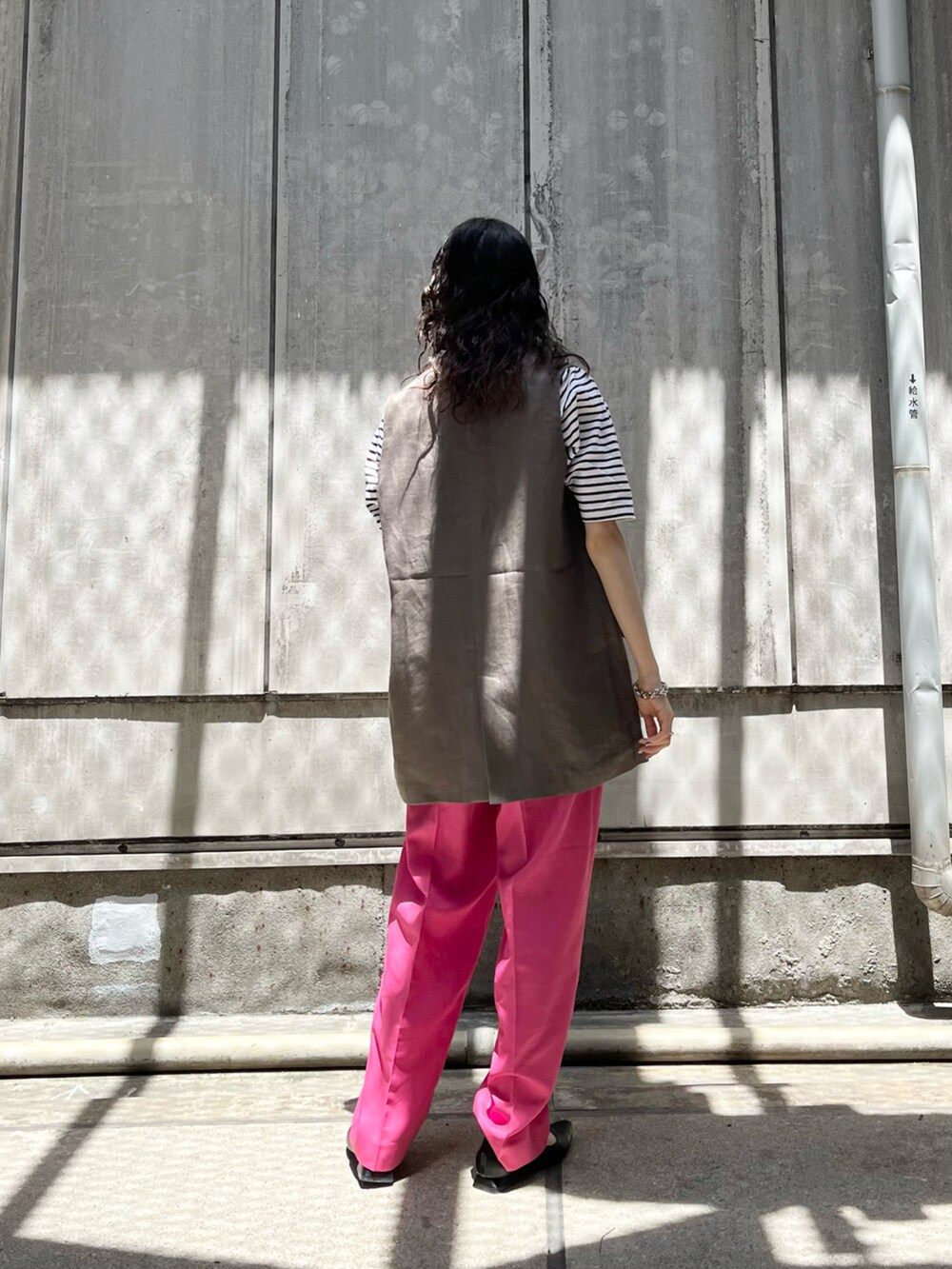 ピンク系のスラックス、グレー系のベストを着用したレディースの夏コーディネートの2枚目の写真