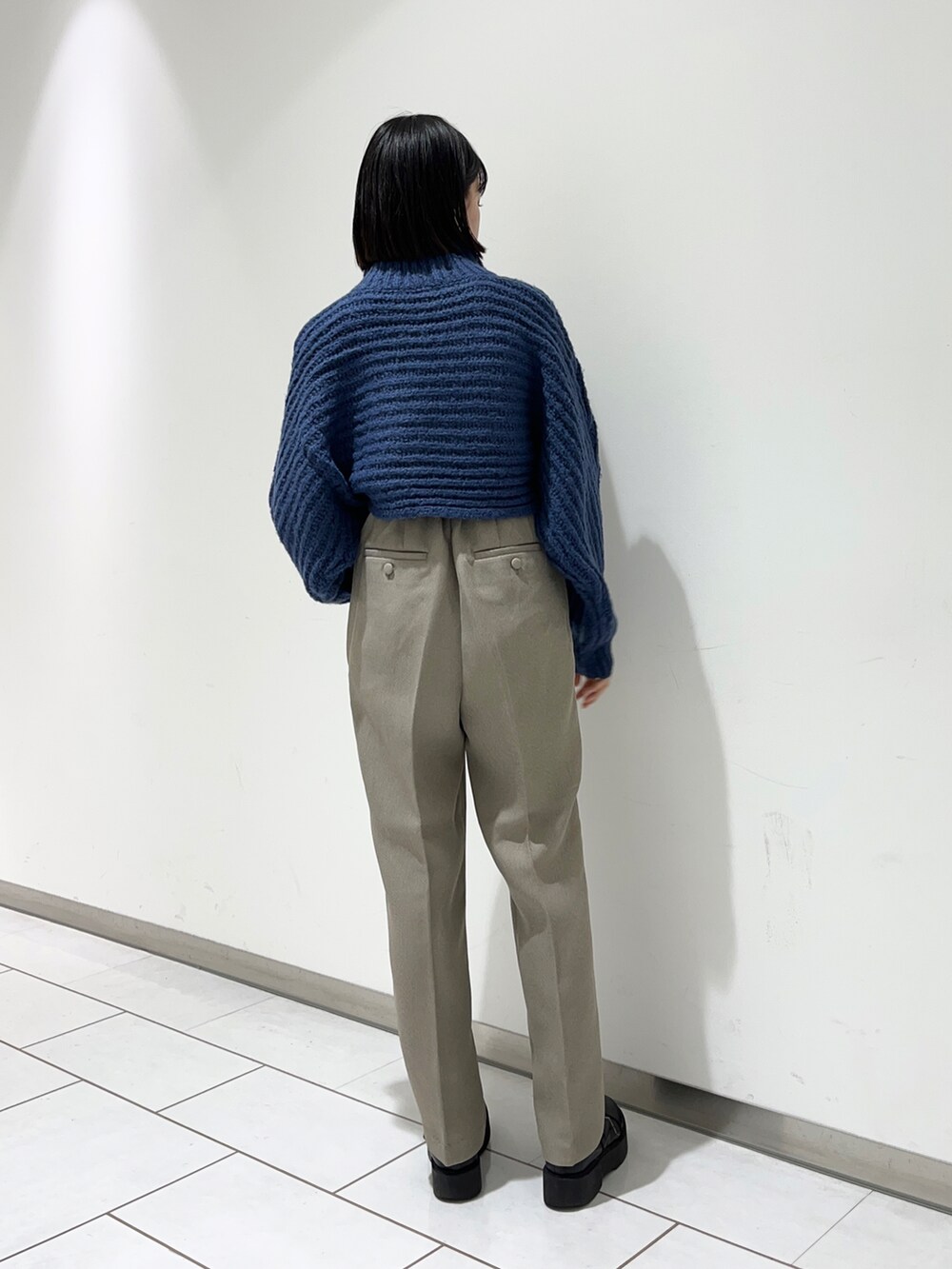 ブルー系のニット/セーター、グレー系のその他パンツ、ブラック系のブーツを着用したレディースの秋コーディネートの2枚目の写真