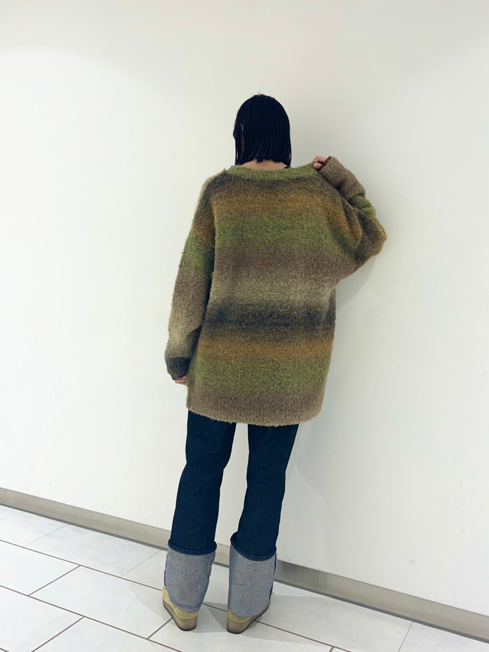 ブルー系のデニムパンツ、ブラウン系のカーディガン/ボレロ、ベージュ系のモカシン/デッキシューズを着用したレディースの冬コーディネートの2枚目の写真