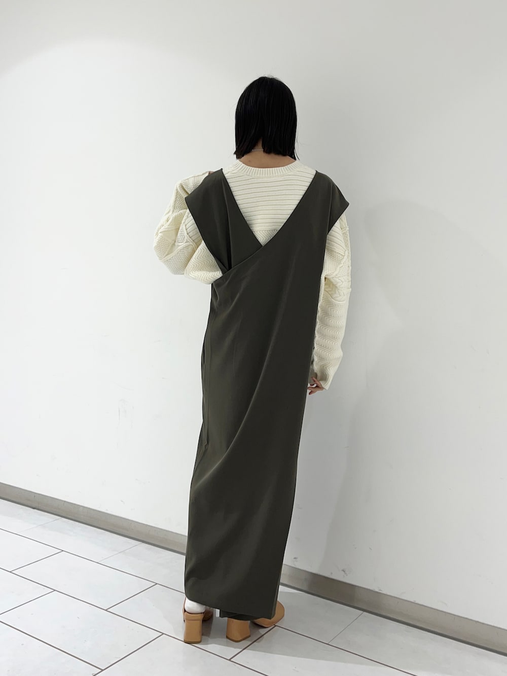 グレー系のワンピース、ホワイト系のニット/セーターを着用したレディースの秋コーディネートの2枚目の写真