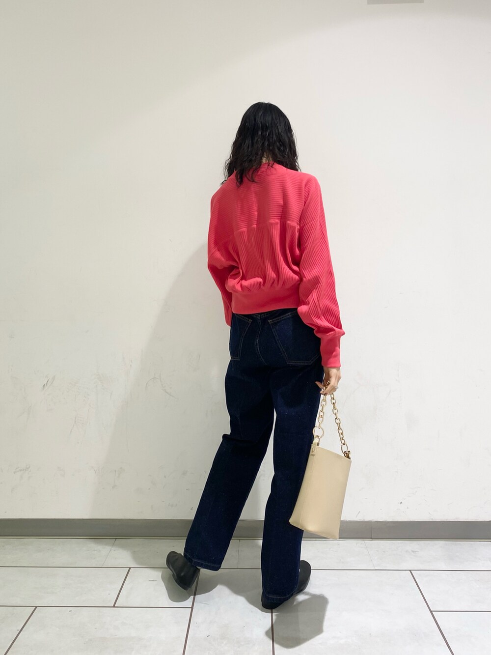 ピンク系のカーディガン/ボレロ、ベージュ系のショルダーバッグ、ブルー系のデニムパンツを着用したレディースの春コーディネートの2枚目の写真