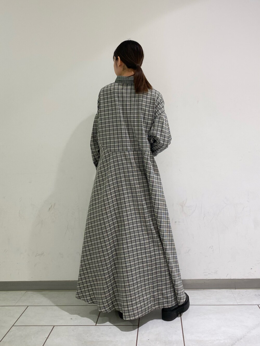 グレー系のワンピース、ブラック系のブーツを着用したレディースの冬コーディネートの2枚目の写真