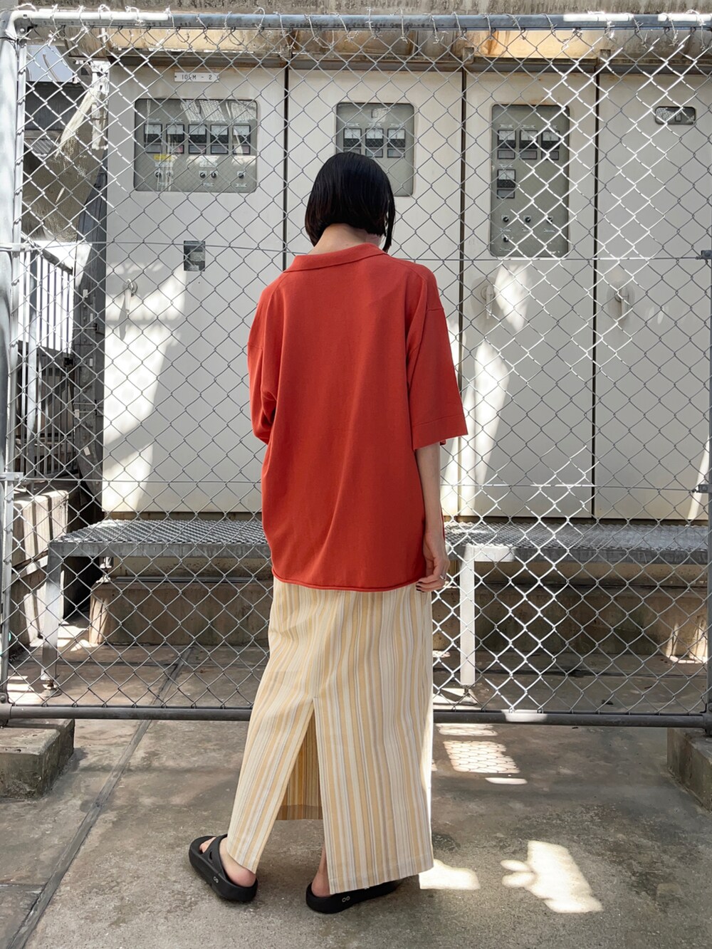 オレンジ系のニット/セーター、ホワイト系のスカートを着用したレディースの夏コーディネートの2枚目の写真