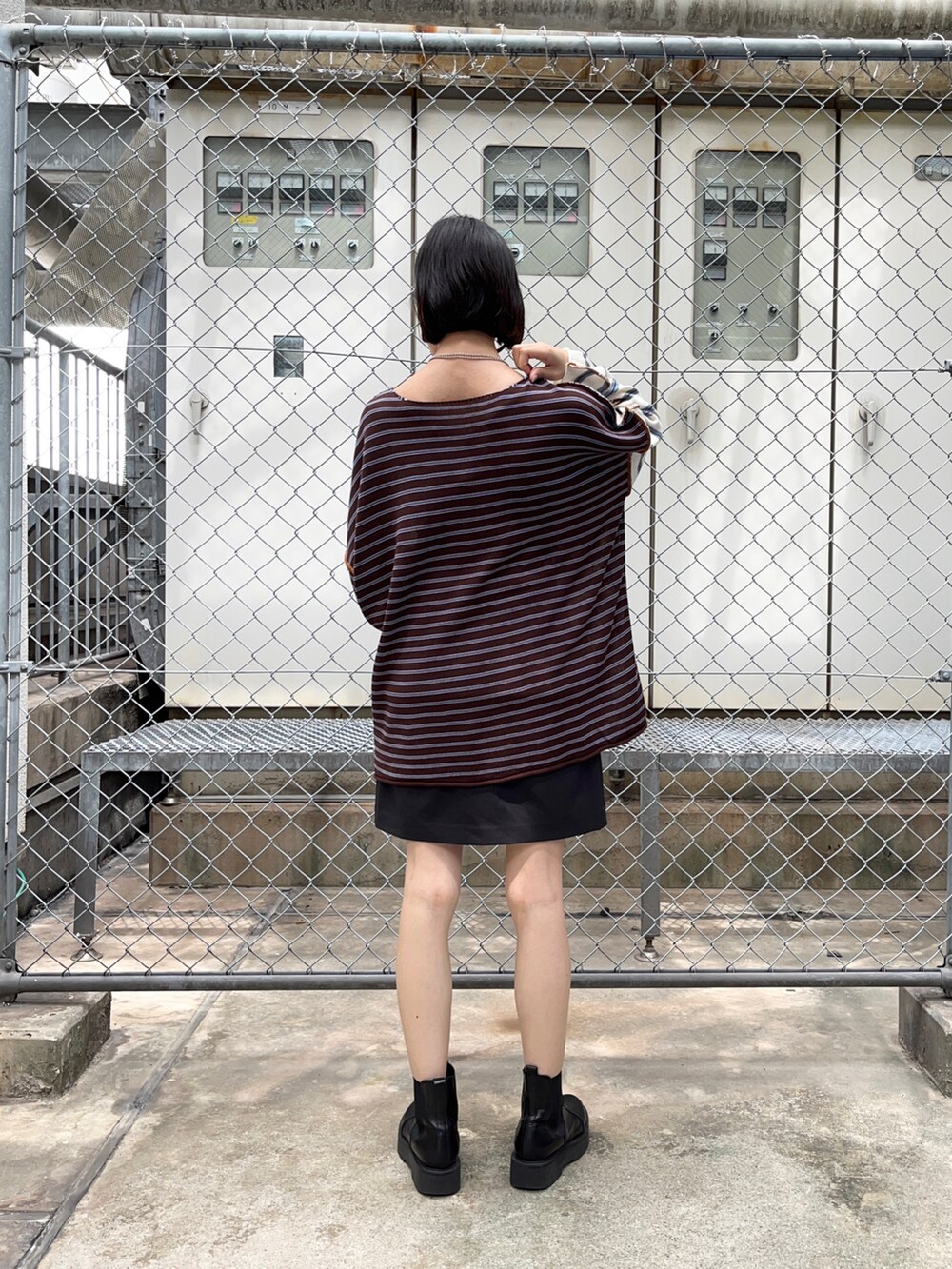 ホワイト系のニット/セーター、グレー系のスカート、ブラック系のブーツを着用したレディースの夏コーディネートの2枚目の写真