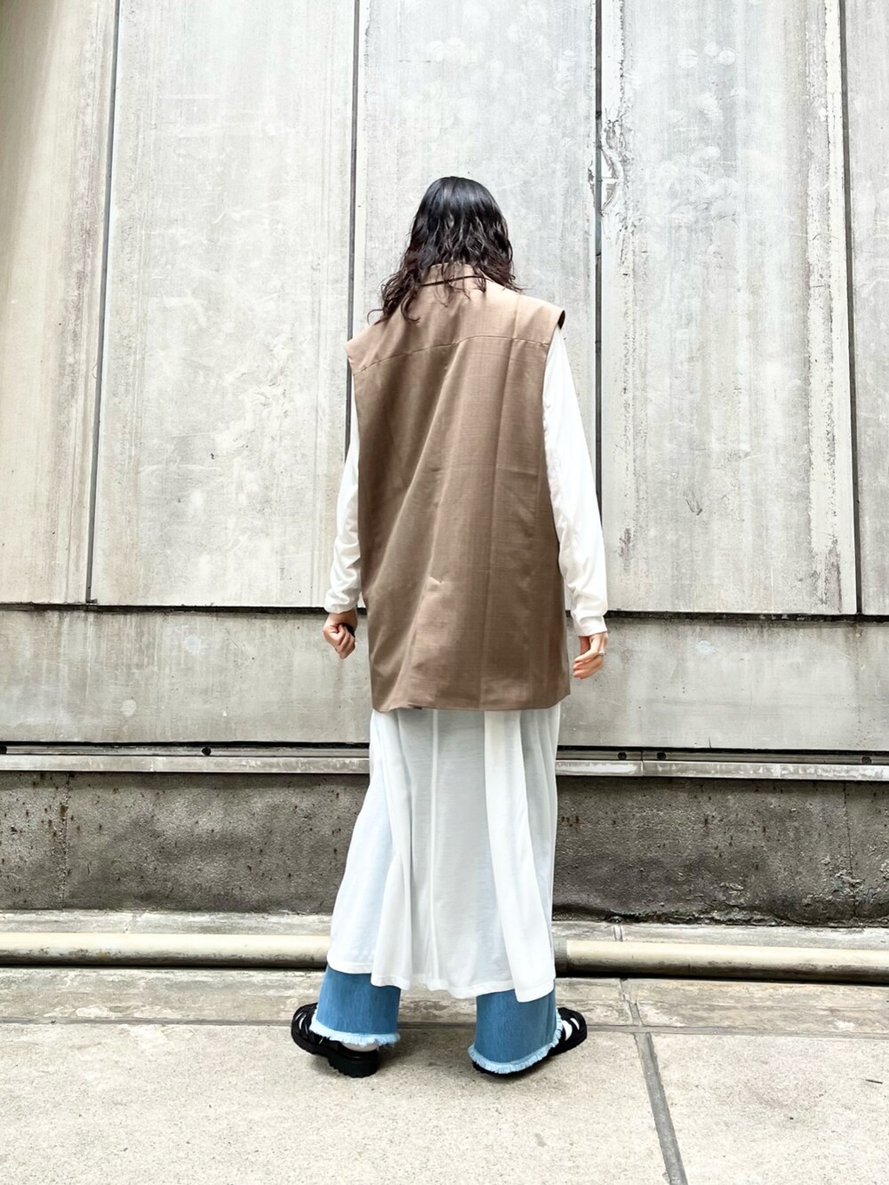 ブラウン系のジャケット/アウター、ホワイト系のワンピース、ブルー系のデニムパンツを着用したレディースの春コーディネートの2枚目の写真