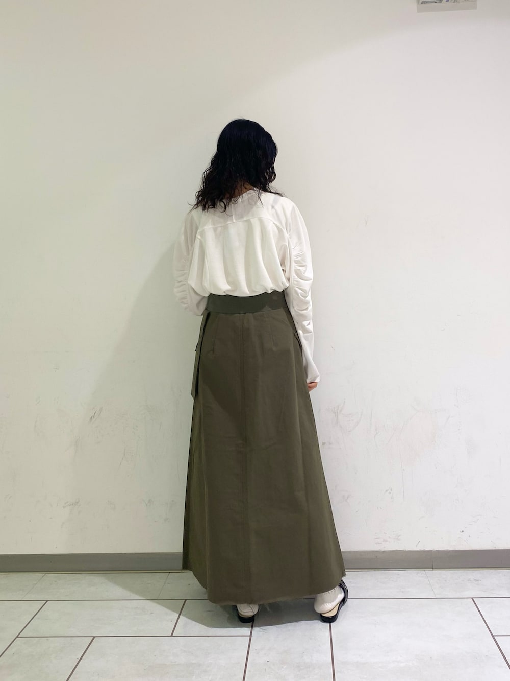 ブラック系のサンダル、グリーン系のスカート、ホワイト系のTシャツ/カットソーを着用したレディースの春コーディネートの2枚目の写真