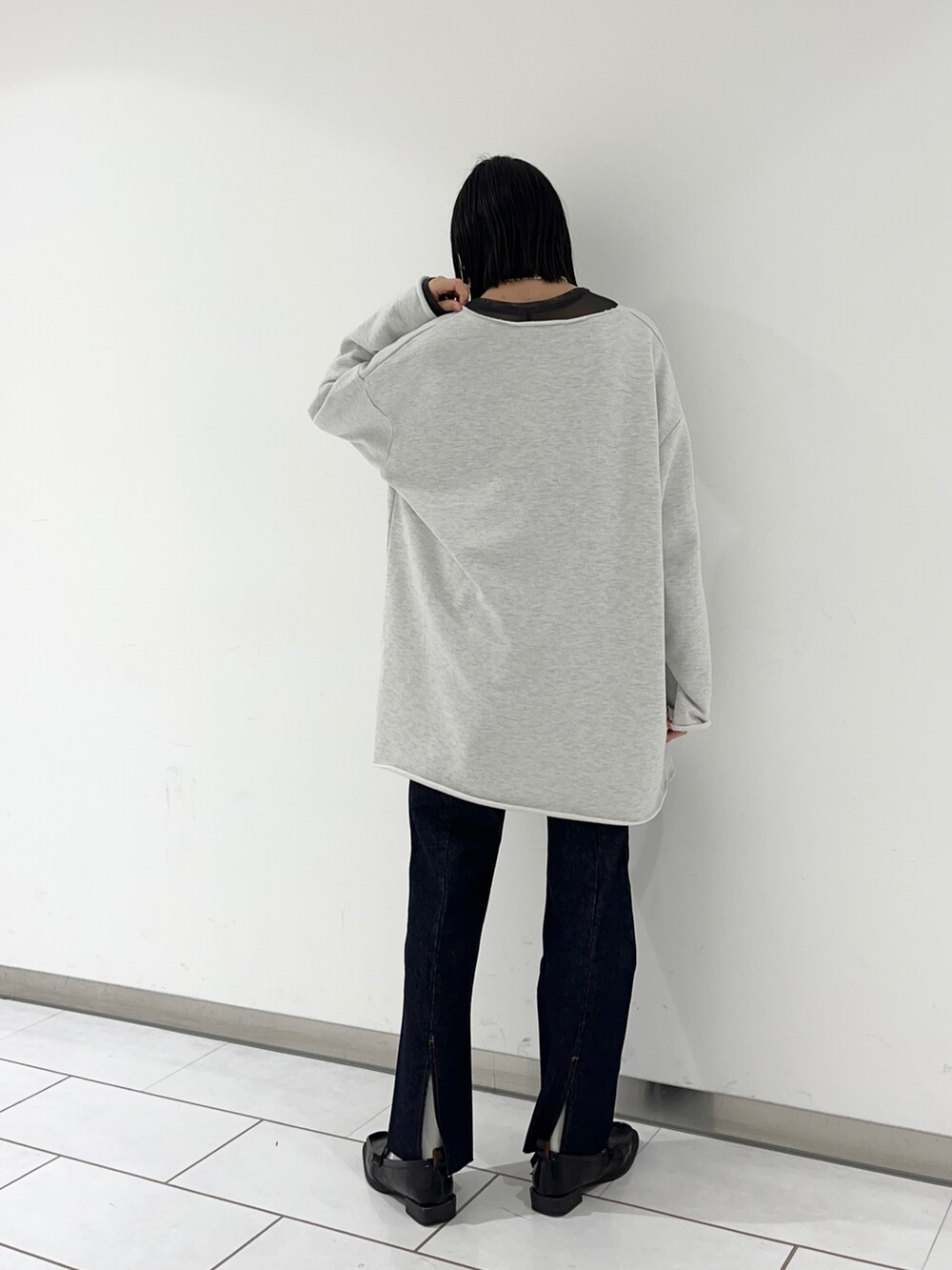 ブラック系のトップス、ベージュ系のTシャツ/カットソー、ブルー系のデニムパンツを着用したレディースの冬コーディネートの2枚目の写真