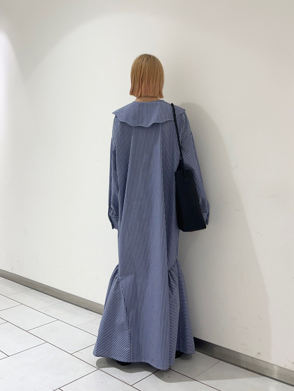 ブラック系のローファー、ブルー系のワンピース、ブラック系のショルダーバッグを着用したレディースの春コーディネートの2枚目の写真