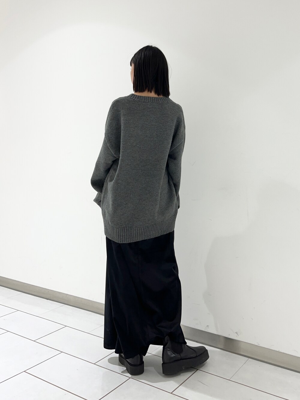 グレー系のニット/セーター、ブラック系のスカートを着用したレディースの冬コーディネートの2枚目の写真