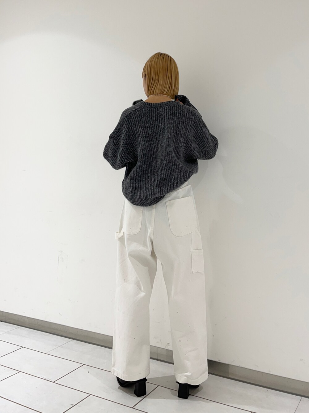 ブラック系のブーツ、ホワイト系のデニムパンツ、グレー系のニット/セーターを着用したレディースの冬コーディネートの2枚目の写真