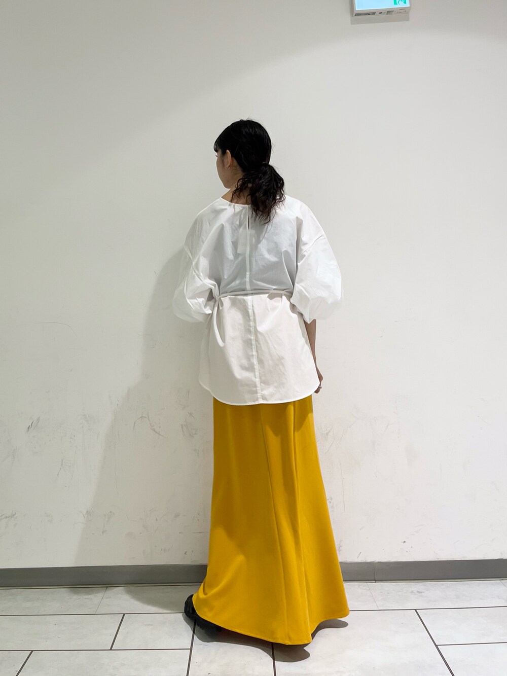 ホワイト系のシャツ/ブラウス、イエロー系のスカート、ブラック系のサンダルを着用したレディースの春コーディネートの2枚目の写真