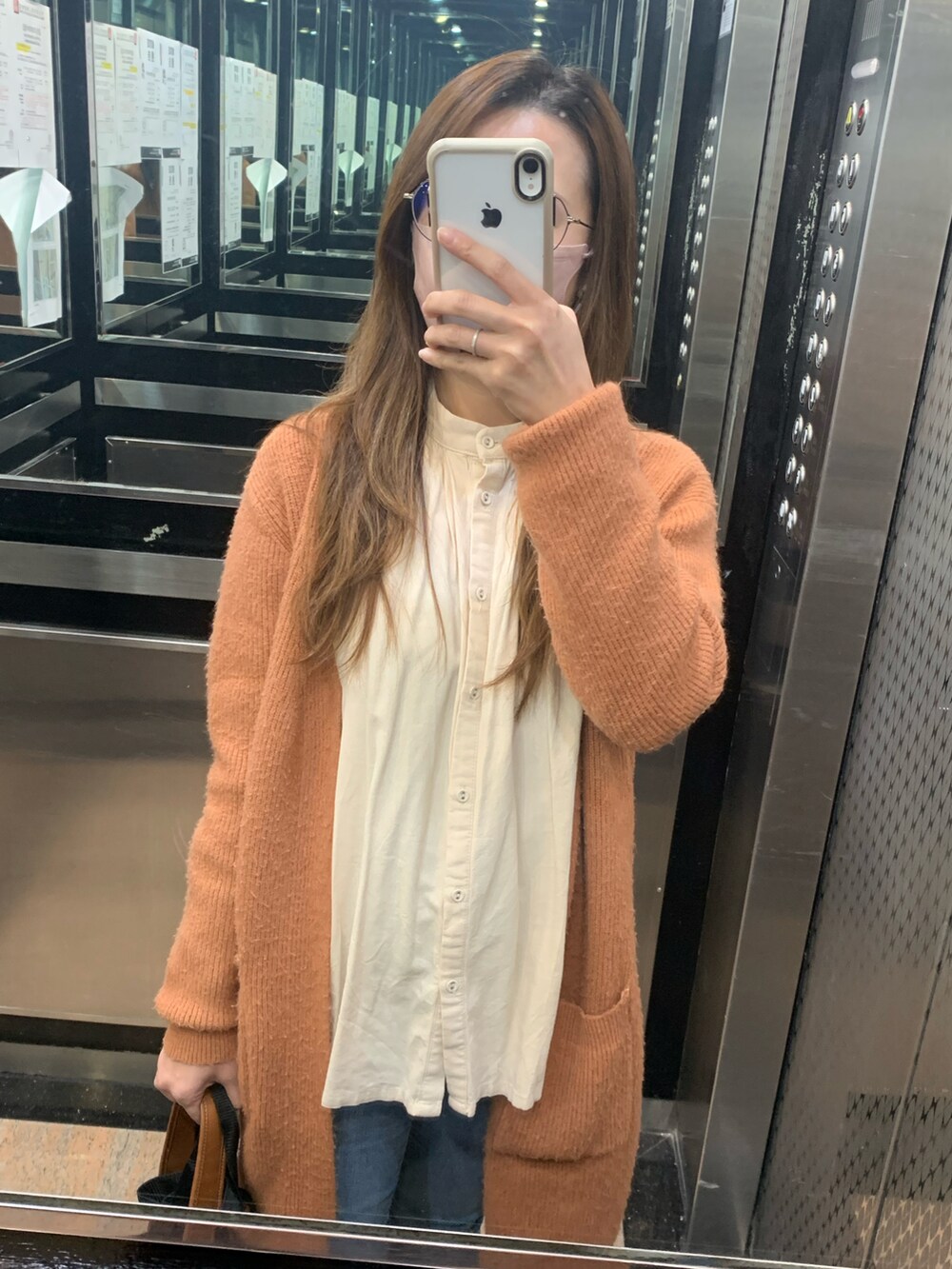 オレンジ系のダッフルコート、ベージュ系のシャツ/ブラウス、ブラウン系のショルダーバッグを着用したレディースの冬コーディネートの2枚目の写真