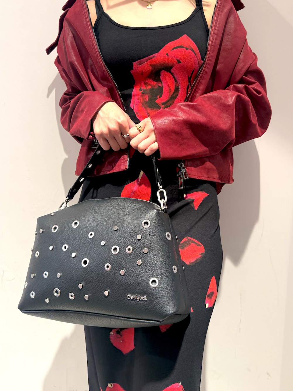 レッド系のライダースジャケット、ブラック系のハンドバッグ、ブラック系のワンピースを着用したレディースの春コーディネートの2枚目の写真