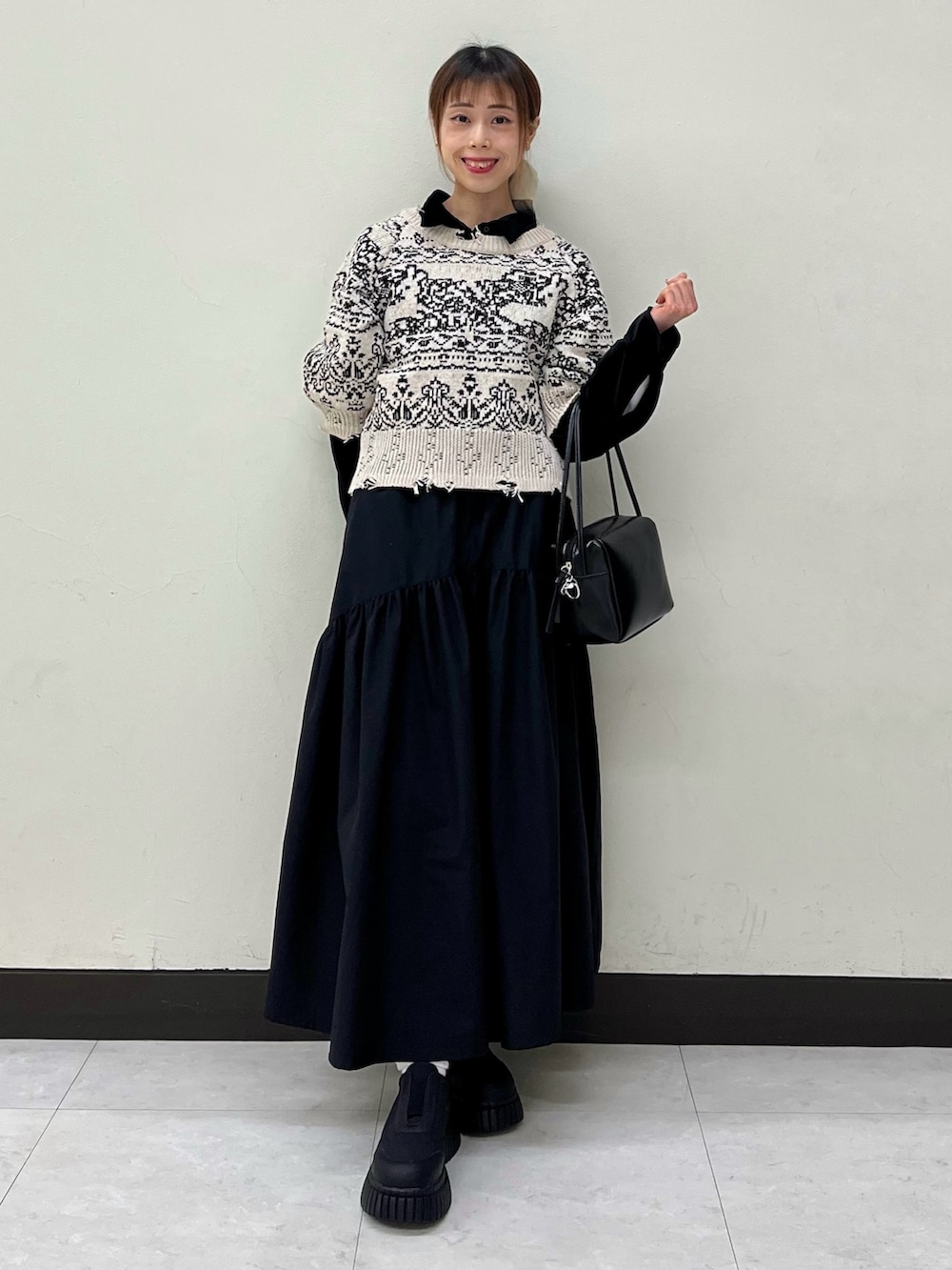 ブラック系のシャツ/ブラウス、ベージュ系のニット/セーター、ブラック系のスカートを着用したレディースの冬コーディネートの2枚目の写真