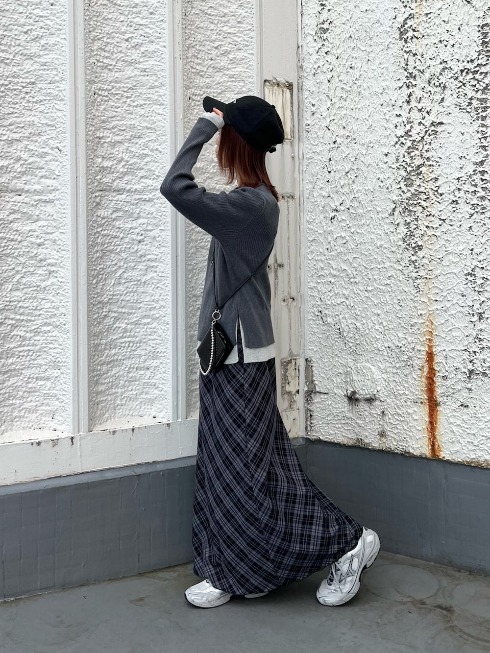 グレー系のニット/セーター、ブルー系のスカート、シルバー系のスニーカーを着用したレディースの秋コーディネートの2枚目の写真