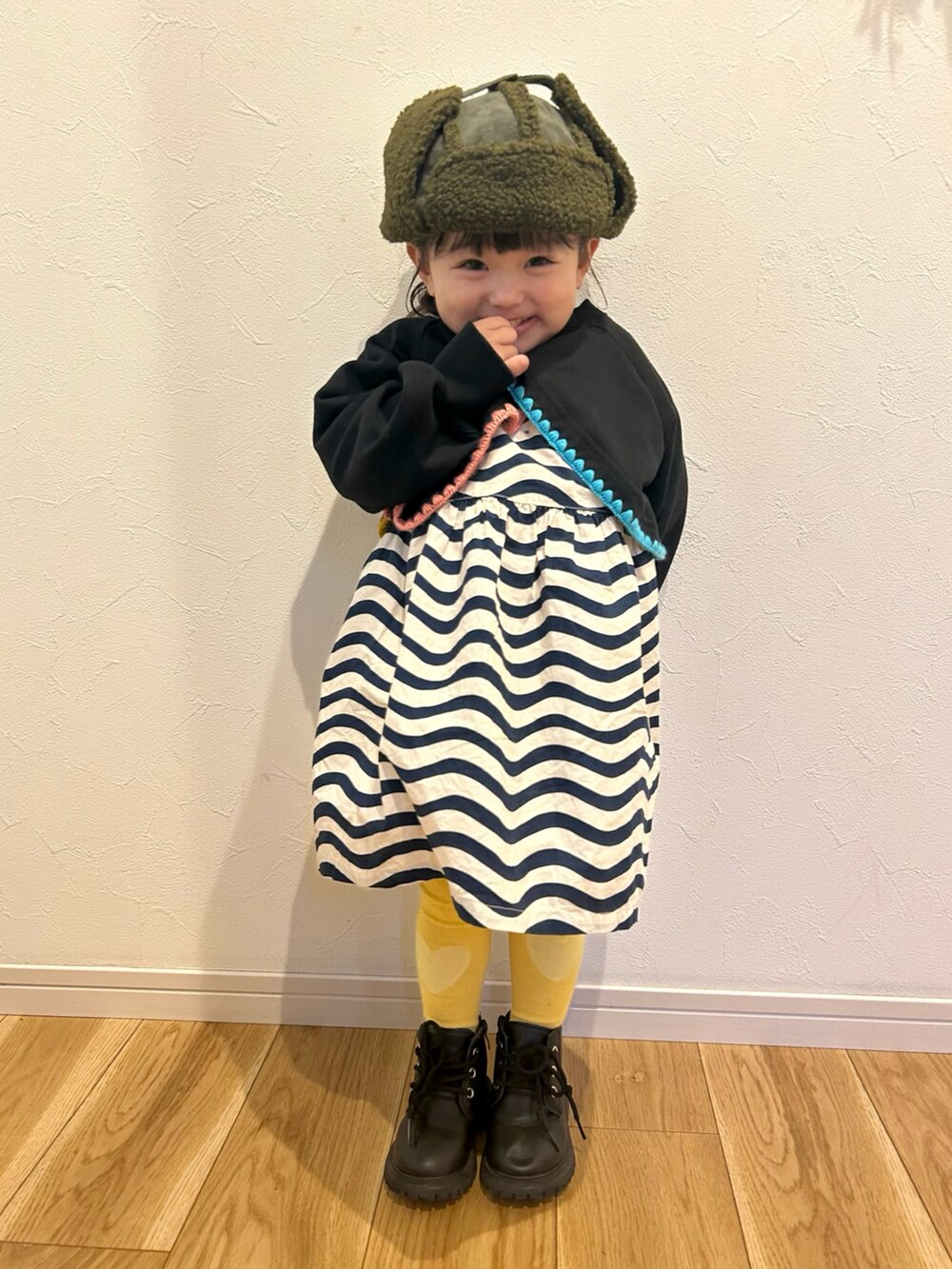 ブラック系のTシャツ/カットソー、ホワイト系のワンピース/ドレス、グリーン系のキャップを着用したキッズの冬コーディネートの2枚目の写真